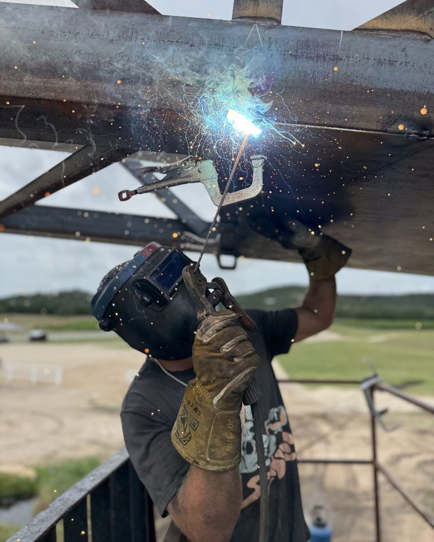 Luke welding overhead on a steel structure, sparks falling